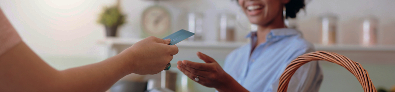 A female cashier takes a credit card from a customer at the counter of a smoothie shop.