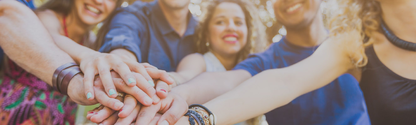 A group of people putting their hands together in a huddle for support.